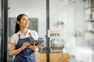 small business owner standing with tablet in front of shop