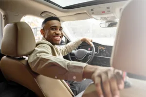 A young person happily test driving a new car