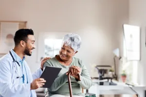 Doctor sharing patient information to older woman while touching her shoulder in his office