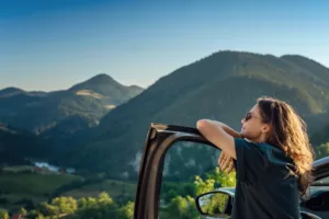 Girl standing by car in the mountains