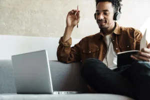 Man wearing headphones looking at laptop on his couch