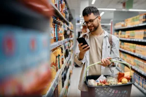 Man shopping in grocery store while looking at phone