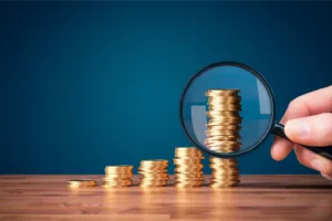 Stack of coins progressively getting larger with a magnifying glass