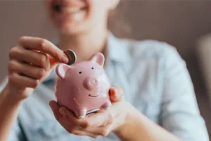 Woman putting a coin into a piggy bank