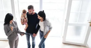 Ariel view of family of three looking at home with real estate agent