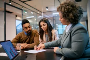 Couple sitting at a desk with a banking professional singing a contract