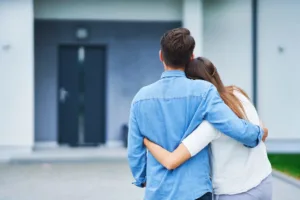 Young couple hugging outside home